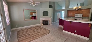 Kitchen featuring tile countertops, brown cabinets, a kitchen breakfast bar, a tiled fireplace, and white appliances