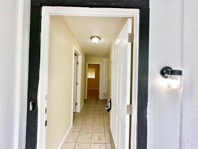 Hall with light tile patterned flooring and a tex