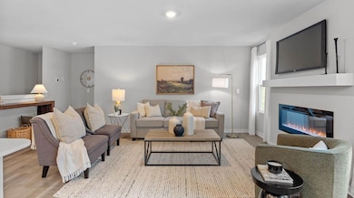 Cozy living room with electric fireplace and an abundance of natural light. Model home, finishes will vary.