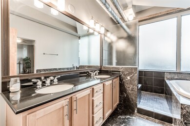 The bath is finished with marble floors and tub/sh