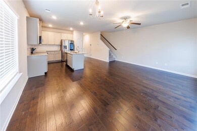 Kitchen with a ceiling fan, stainless steel refrigerator with ice dispenser, an island with sink, dark wood-style floors, and open floor plan