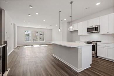 Kitchen with appliances with stainless steel finishes, dark wood-type flooring, a kitchen island, white cabinetry, and recessed lighting