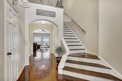 Impressive entry with high ceilings, beautiful hardwood flooring and wrought iron and wood staircase.