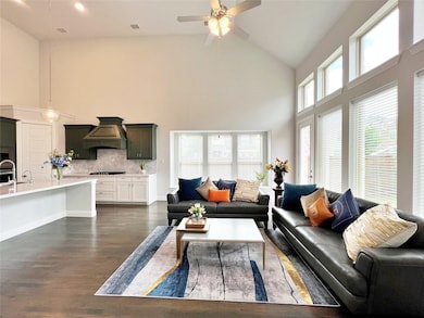 Living room with high vaulted ceiling, a healthy amount of sunlight, ceiling fan, and dark hardwood / wood-style flooring

