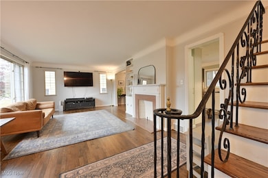 Living room with wood finished floors, stairway, and ornamental molding