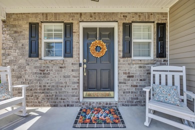 Entrance to property with covered porch and brick siding