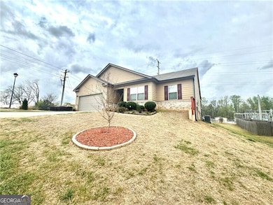 View of front of home featuring driveway, a front yard, cooling unit, brick siding, and a garage