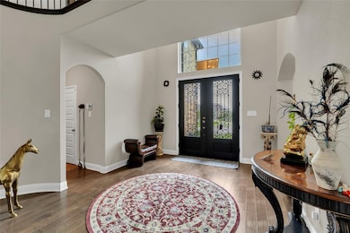 Foyer featuring arched walkways, a towering ceiling, hardwood / wood-style flooring, and french doors