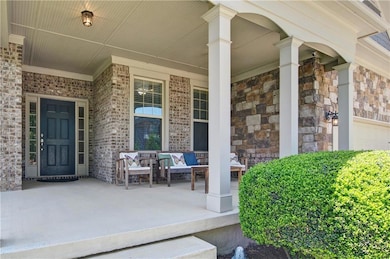 Entrance to property featuring covered porch, bric