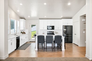 Kitchen with black appliances, light countertops, white cabinets, a kitchen island, and recessed lighting