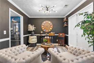 Living room featuring a textured ceiling, a chandelier, wood finished floors, and crown molding