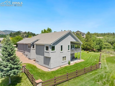 Back of property with a balcony, a lawn, stucco siding, and a tiled roof