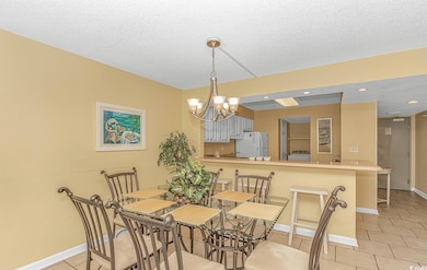 Dining area with light tile patterned flooring, a chandelier, a textured ceiling, and recessed lighting