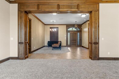 Carpeted foyer featuring baseboards and crown molding