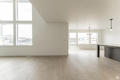 Additional living space with light wood-style flooring and a chandelier