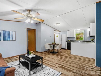 Open concept living and kitchen area with hardwood flooring, white cabinetry, and recessed lighting. - 2271 Gouges Creek Rd, Spruce Pine, NC 28777