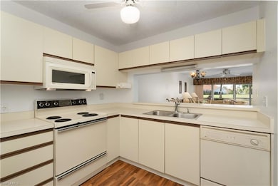 Kitchen with ceiling fan, white appliances, cream cabinetry, a textured ceiling, and light countertops