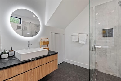 Full bath with vanity, a shower stall, baseboards
