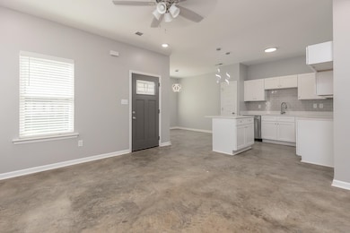 Kitchen with concrete floors, ceiling fan, a kitchen island, tasteful backsplash, and white cabinets