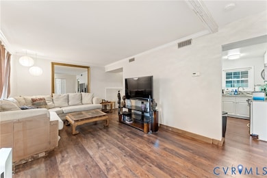 Living room with dark wood-style floors and ornamental molding