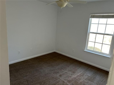 Carpeted spare room featuring ceiling fan