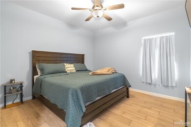 Bedroom with light wood finished floors, baseboards, and a ceiling fan
