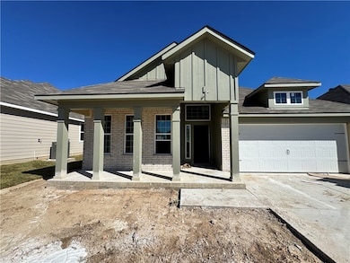 View of front of property with brick siding, covered porch, driveway, board and batten siding, and roof with shingles