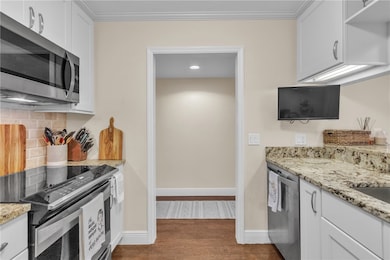 Gorgeous renovated kitchen w/ special pantry door, SS appliances including slide-in range, granite counters, crown molding, tumbled marble backsplash, under counter lighting & engineered wood floors!