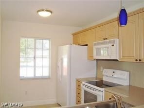 Kitchen with pendant lighting, light brown cabinetry, and white appliances