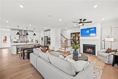 Living room featuring recessed lighting, light wood finished floors, a brick fireplace, and a ceiling fan
