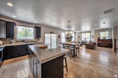 Kitchen with open floor plan, recessed lighting, light wood-type flooring, a center island, and decorative backsplash