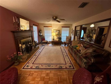 Living area with a brick fireplace, ceiling fan, and a textured ceiling
