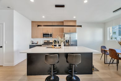 Kitchen with pendant lighting, an island with sink, appliances with stainless steel finishes, a kitchen bar, and recessed lighting