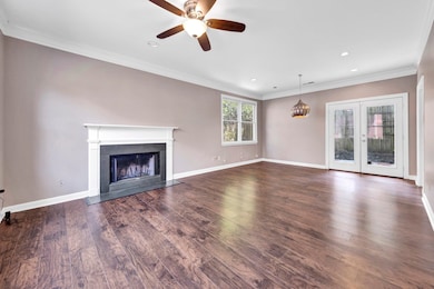 Unfurnished living room featuring a fireplace with flush hearth, ornamental molding, ceiling fan, dark wood-style flooring, and recessed lighting