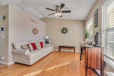 Living area featuring vaulted ceiling, light wood-type flooring, and a ceiling fan