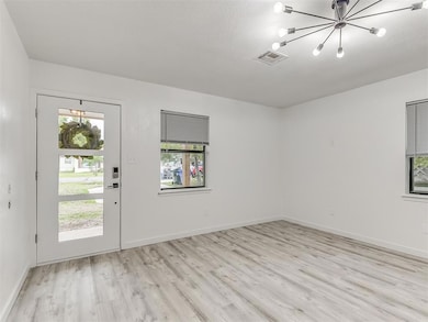 Entryway with light wood-type flooring, a chandelier, and a textured ceiling