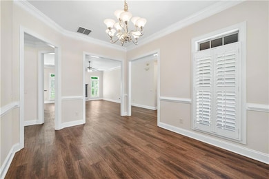 Unfurnished dining area featuring a chandelier, dark wood-style floors, ornamental molding, and a ceiling fan