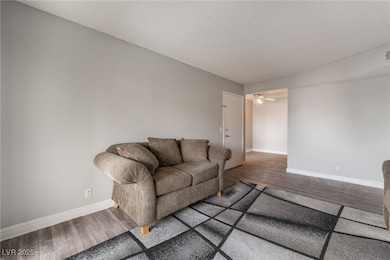 Living room with wood finished floors, a textured ceiling, and a ceiling fan