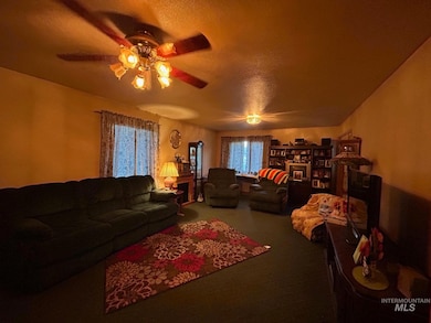 Carpeted living area with a textured ceiling and ceiling fan