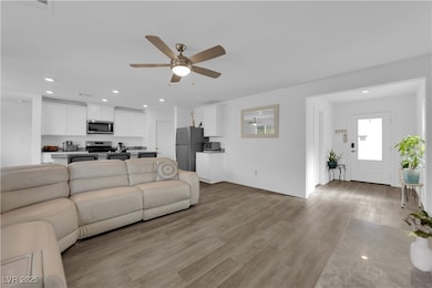 Living room featuring light wood-type flooring, recessed lighting, and a ceiling fan