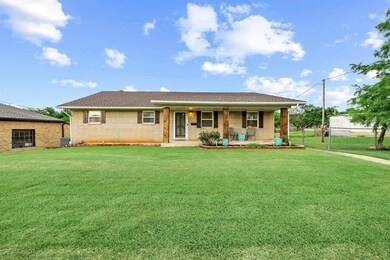 Single story home with brick siding, covered porch, and roof with shingles