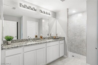 Bathroom featuring tile flooring, tiled shower, double sink, and large vanity