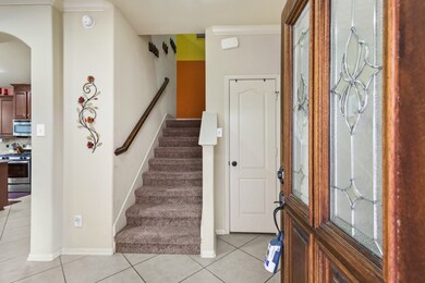 Elegant Entryway offers terrific tile flooring, easy access to the upstairs living space from stairs with plush carpeting, and crown molding.