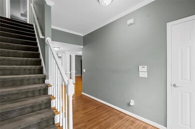 Staircase with crown molding, wood finished floors, and decorative columns