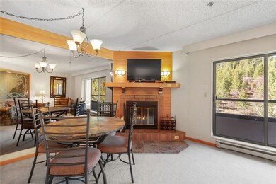 Carpeted dining room with a chandelier, a brick fireplace, baseboard heating, and a textured ceiling