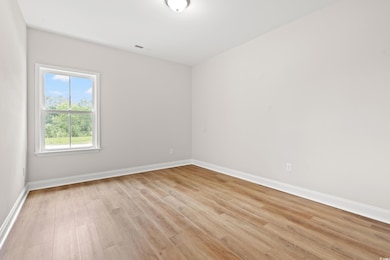 Spare room featuring light wood-style flooring and baseboards