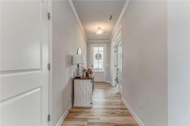 Entryway with ornamental molding, light wood-type flooring, and baseboards