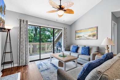 Living area with wood finished floors, a ceiling fan, a textured ceiling, lofted ceiling, and baseboards