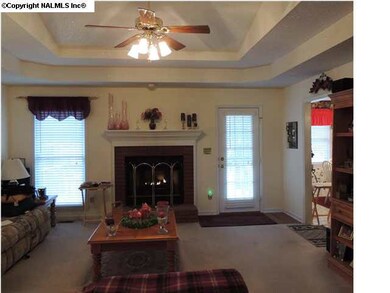 Family Room with double try ceiling, gas log fireplace and huge windows looking out over deck, pool and acreage.