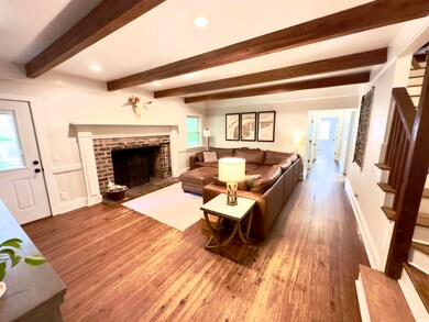 Living area with wood finished floors, a fireplace, stairway, beam ceiling, and recessed lighting